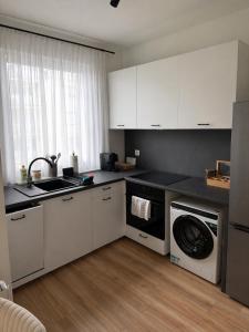 a kitchen with white cabinets and a washing machine at PikApart in Olsztyn