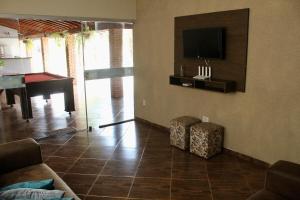a living room with a television and a piano at Chacara Mariana in Olímpia