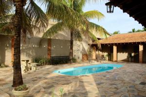 a swimming pool in a courtyard with palm trees at Chacara Mariana in Olímpia