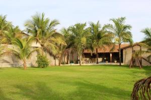 a yard with palm trees in front of a building at Chacara Mariana in Olímpia