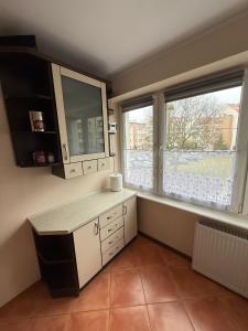 a kitchen with a counter and two large windows at Apartament MIRO in Ostróda +2 photos