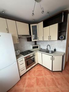 a kitchen with white cabinets and a sink and a refrigerator at Apartament MIRO in Ostróda