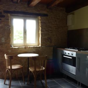 a kitchen with a table and two chairs and a window at Les choses de la vie in Saint-Alvère