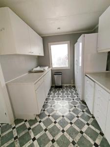 a kitchen with white cabinets and a checkered floor at Familjenest in Bollnäs