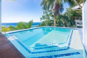 a swimming pool with the ocean in the background at Top Ridge Views home in Roatán