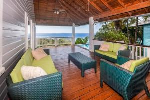 a porch with chairs and tables and the ocean at Top Ridge Views home in Roatán