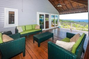 a porch with couches and chairs on a deck at Top Ridge Views home in Roatán