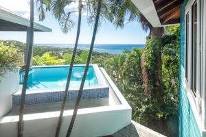 a house with a swimming pool and palm trees at Top Ridge Views home in Roatán +46 photos