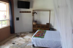 a bedroom with a bed and a window and a television at Hotel Kocai Izamal in Izamal