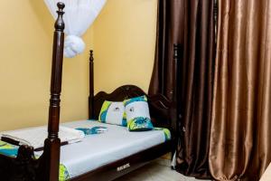 a small bedroom with a bed with a canopy at Peak Motel in Kasese