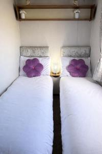 two beds in a small room with purple pillows at Rosie's Seton Retreat in Port Seton