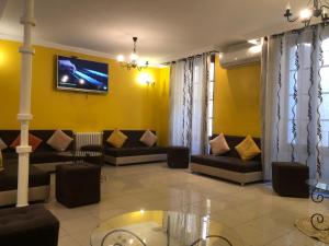 a living room with couches and a tv on a wall at Hotel El Maghreb in Constantine