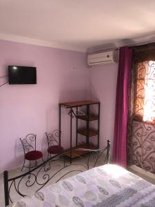 a bedroom with a bed and two red chairs at Hotel El Maghreb in Constantine