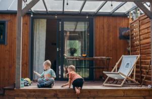 two children are sitting on the porch of a house at Ostoja Wycinki domki letniskowe in Jaszczerz