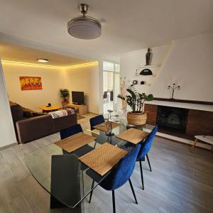 a living room with a glass table and blue chairs at Casa en La Marina cerca de la Playa y Pinada in Elche