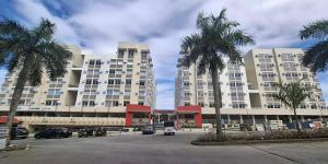 two tall buildings with palm trees in a parking lot at Fullerton suites C homestay in Silang