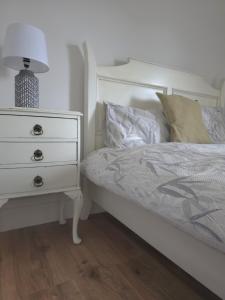 a bedroom with a white bed with a dresser and a night stand at The Wild Atlantic Townhouse in Enniscrone