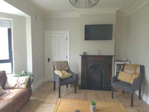 a living room with a couch and chairs and a fireplace at The Wild Atlantic Townhouse in Enniscrone