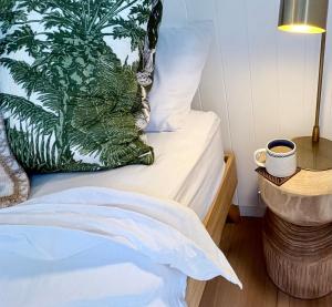 a bed with a plant pillow and a cup of coffee at Moana bungalow in Hideaway Bay