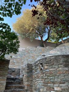 Eine Steinmauer mit Bäumen im Hintergrund in der Unterkunft August Andros in Ándros