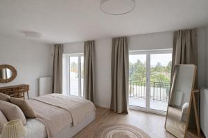 a white bedroom with a bed and a balcony at Theodora Residence in Balatonalmádi +13 photos