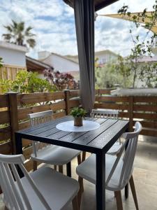 a wooden table with white chairs and a plant on it at Yanna's Apartments in Sidari
