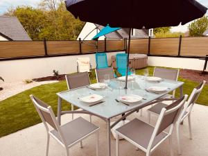 a table with chairs and an umbrella on a patio at Maison moderne 3 chambres SPA-jacuzzi mai-septembre in Cerelles