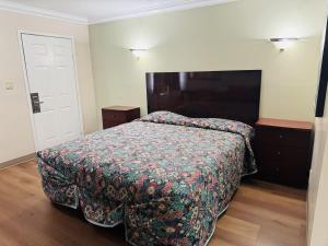 a bedroom with a bed with a blanket on it at Imperial Inn & Suites in Norwalk