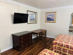 a bedroom with a desk and a bed and a desk and a television at Imperial Inn & Suites in Norwalk