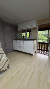 a large kitchen with white cabinets and a large window at Casinha das bonecas in Adenodeiro +13 photos