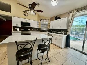 a kitchen with a large island with two bar stools at Acreage Oasis - 5 Bedrooms, Pool, Space, Serenity in West Palm Beach