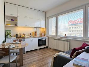 a kitchen with white cabinets and a table in a room at Prime Main Square Location in Skopje