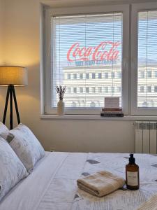 a bed in a bedroom with a cocacola sign in a window at Prime Main Square Location in Skopje