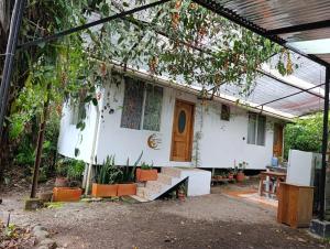 ein kleines weißes Haus mit einer Pergola in der Unterkunft Mindomundo Home in Mindo