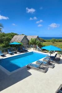 a swimming pool with lounge chairs and umbrellas at West Rock Villas in Saint James