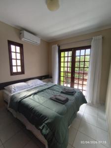 a bedroom with a large bed and two windows at Chalé Esmeralda in Gravatá +22 photos