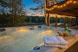 a jacuzzi tub with a pergola and a river at The Kingfisher Lodge in Cornell