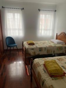 a bedroom with two beds and a blue chair at Charming Blue House in Furnas