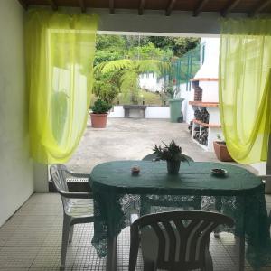 a green table and chairs on a patio at Charming Blue House in Furnas +14 photos