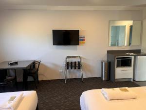 a hotel room with two beds and a tv on the wall at Merewether Motel in Newcastle