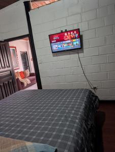 a bedroom with a bed and a tv on the wall at Rincón de Paz y Tranquilidad in Ambato