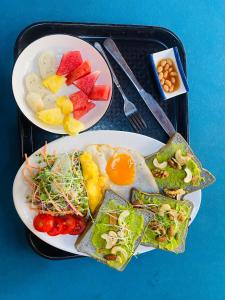 a tray with two plates of food with fruits and vegetables at Big J Hostel in Ninh Binh