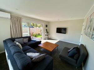 a living room with a blue couch and a table at Hanmer Time in Hanmer Springs
