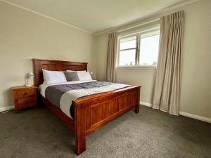 a bedroom with a wooden bed and a window at Hanmer Time in Hanmer Springs +16 photos