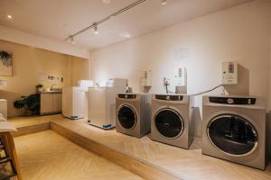 a laundry room with three washing machines in it at Meworld Hotel - Taipei Main Station in Taipei