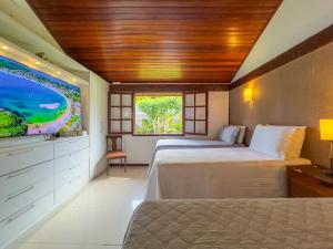 two beds in a room with a flat screen tv at Búzios House Oficial in Búzios +65 photos