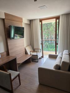a living room with a couch and a tv at Flat Hotel Pedra Azul in Pedra Azul