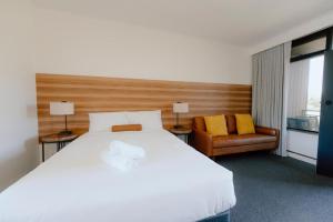 a bedroom with a large white bed and a chair at Canberra Park Motel in Canberra
