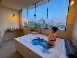 a woman in a bath tub with a window at nirvana pyramids view in Cairo