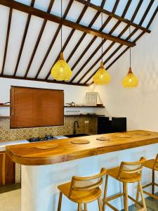 a kitchen with a large wooden counter and chairs at VILLA Santay byAdiba in Gili Islands